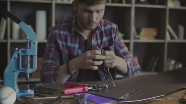 Muž šicí jehly v domácí dílně. Řemeslník vydělávání kůže peněženka — Stock video