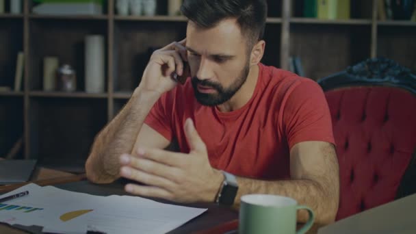 Um homem furioso a falar ao telefone na secretária. Homem de negócios irritado falando no telefone móvel — Vídeo de Stock