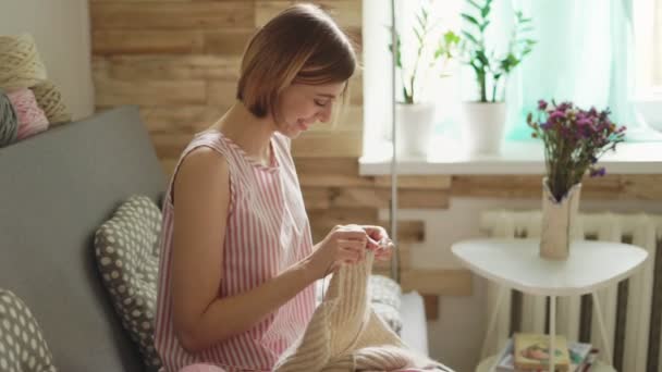 Femme heureuse assise sur un canapé et tricotant du fil de laine. hobby de femme — Video