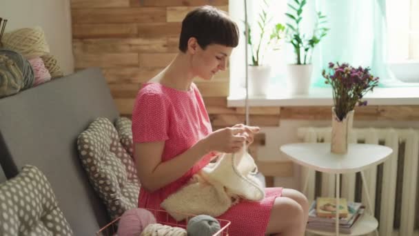 Mujer creativa tejiendo lana sentada en el sofá en la ventana de fondo — Vídeos de Stock