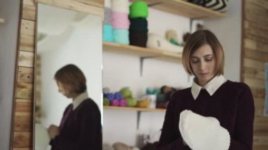 Örme kap ile genç bir kadın ayakta açık ayna. Kadın Tekstil atölyesinde