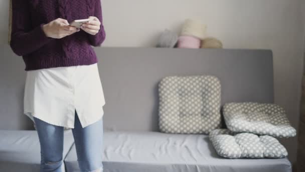 Mujer joven usando el teléfono móvil en la habitación de casa. Chica escribiendo mensaje en el teléfono inteligente — Vídeos de Stock