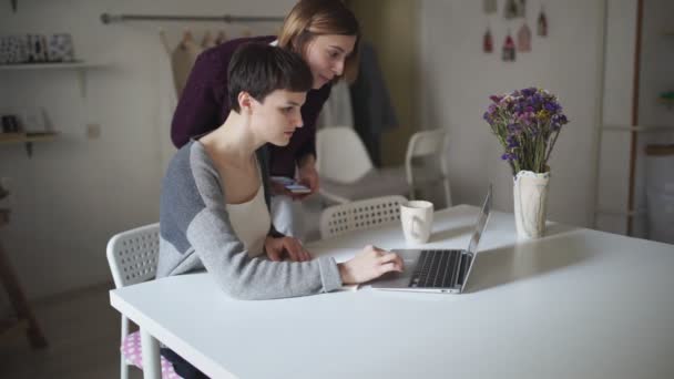 Estudiantes buscando internet en un ordenador portátil. Dos mujeres buscando noticias — Vídeos de Stock