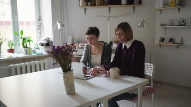 Dos alumnas en la mesa usando cuaderno para aprender en línea en casa — Vídeo de stock
