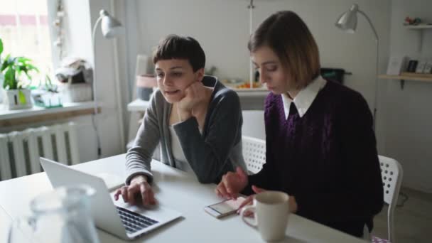 Twee vrouw vrienden met behulp van laptop zitten aan tafel — Stockvideo
