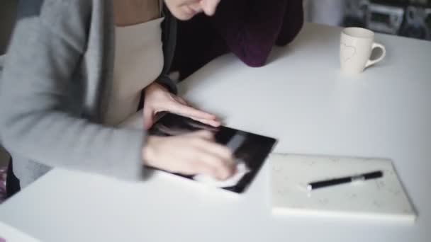 テーブルの上に横たわる布で表面スクリーンのタブレット pc を拭く女性の手 — ストック動画