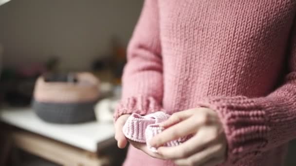 Manos femeninas sosteniendo botines de bebé. Zapatos de punto hechos a mano para niños — Vídeos de Stock