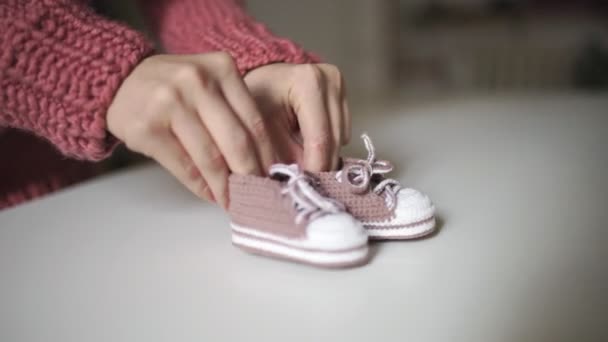 Mãos de mãe brincando com botas de bebê de malha. Roupa de malha para crianças — Vídeo de Stock