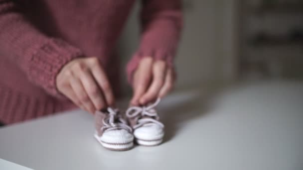 Mor händerna spelar med rosa baby tossor. Sticka kläder för barn — Stockvideo