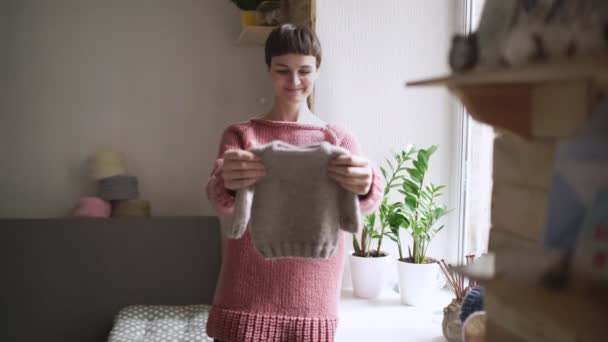 Femme tenant dans les mains des vêtements tricotés pour bébé. Vêtements faits à la main pour enfants — Video