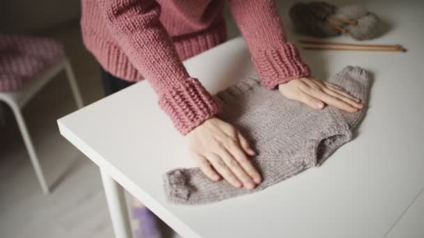 Woman expecting baby looking at knitted sweater lying on table. Handmade clothes — Stock Video