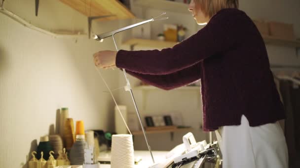 ワーク ショップのテーブル上に立っているマシンを編んで糸を引っ張るクラフト女性 — ストック動画