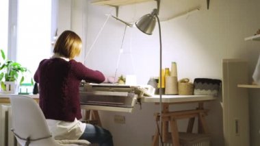 Genç kadın Tekstil dokuma makine atölyesinde masada oturup örgü