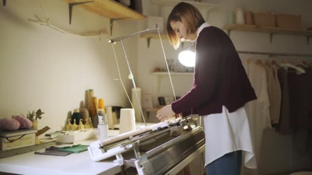 Jonge vrouw die werkt op de machine in huis workshop breien — Stockvideo