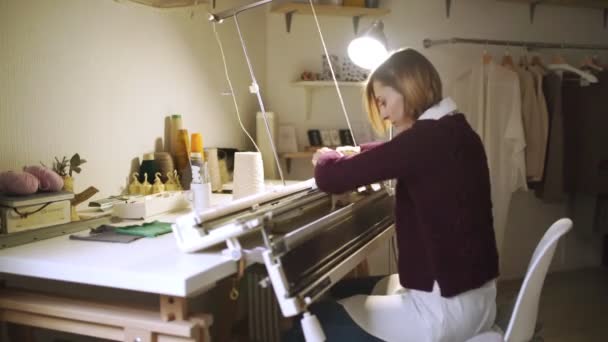 Kreative Frau fertigt Stricktextilien auf Webmaschine in Werkstatt — Stockvideo