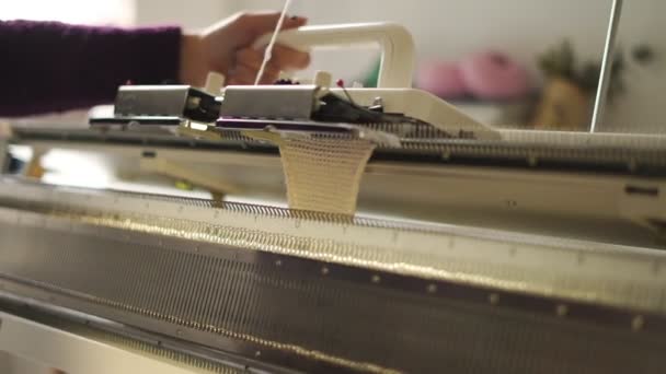 Manos femeninas trabajando en la máquina de tejer en el taller. Tejido de punto de lana — Vídeo de stock