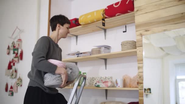 Estanterías de mujer artesanal bola de lana en estante en la tienda textil. Mujer en tienda textil — Vídeos de Stock
