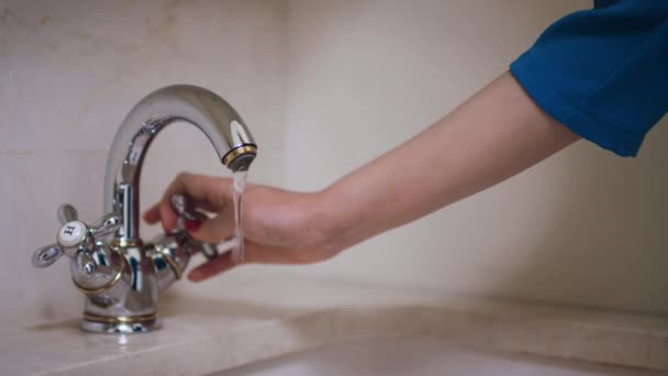 Vrouw hand draaien knop en het openen van waterkraan in de badkamer — Stockvideo