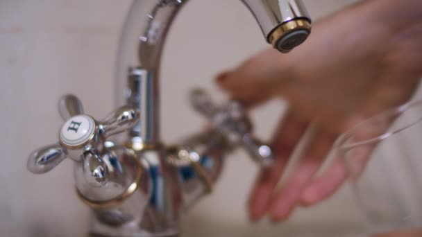Mujer mano verter agua en el vidrio del grifo de agua en la cocina — Vídeo de stock