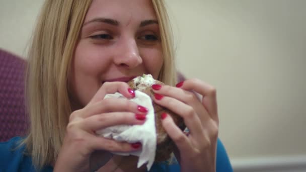 Πρόσωπο νεαρή γυναίκα δάγκωμα νόστιμα σάντουιτς και να αναζητούν σε κάμερα — Αρχείο Βίντεο