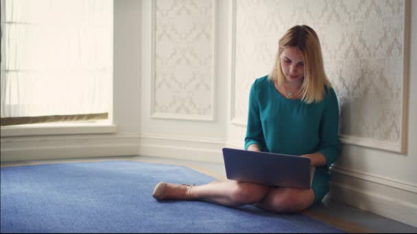Belle femme assise sur le sol dans la chambre et utilisant un ordinateur portable . — Video