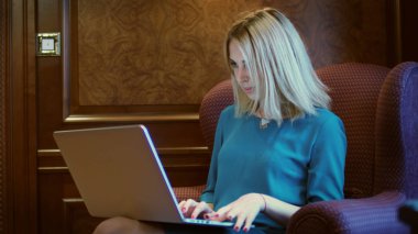 Lüks sandalyede oturan ve tipik dizüstü klavye üzerinde güzel kadın