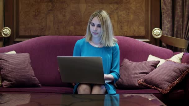 Belle femme assise sur un canapé de luxe et travaillant sur un ordinateur portable 