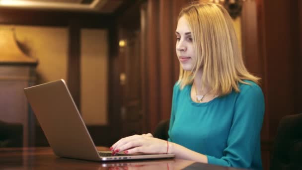 Mujer joven mirando en el ordenador portátil de pantalla y escribiendo en el teclado — Vídeo de stock