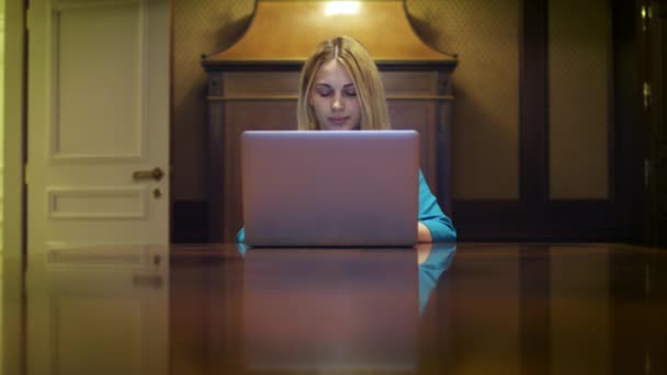 Femme sérieuse travaillant sur ordinateur portable assis à la table dans le studio à la maison — Video