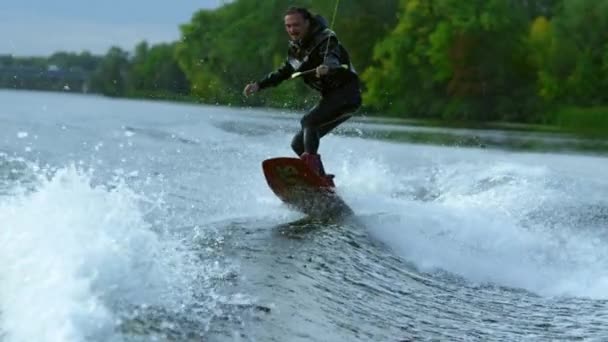 Νεαρός άνδρας σχετικά wakeboard τεμαχίζοντας ποταμού κύματα σε αργή κίνηση. Ακραία διακοπές — Αρχείο Βίντεο