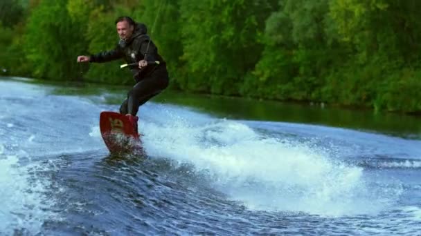 Hombre montando a bordo en olas. Despierta entrenamiento jinete de embarque en barco wakeboard — Vídeos de Stock