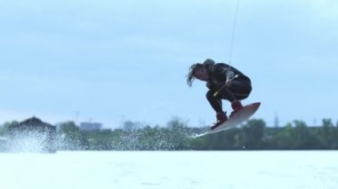 Erkek wakeboarder nehirde suyun üstünde yüksek atlama wakeboard sürme