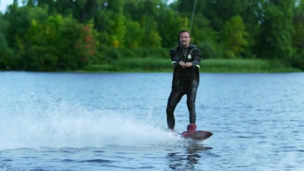 Νεαρός άνδρας ιππασία wakeboard στη λίμνη το καλοκαίρι. Ο άνθρωπος απολαμβάνοντας ακραία διακοπές — Αρχείο Βίντεο