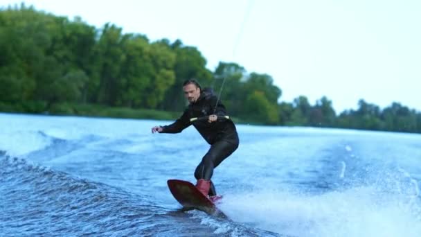 Wakeboarder водные лыжи на реке за лодкой. Посадка на вейк — стоковое видео