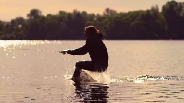 Man start wakebording bij zonsondergang. Extreme levensstijl. Rijden op water — Stockvideo