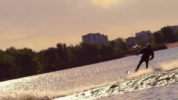 Esquiador aquático se movendo rápido em salpicos de água ao pôr do sol. Esportes aquáticos extremos — Vídeo de Stock