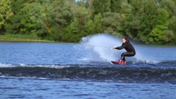 Wakeboarder jumping over water wave. Slim man wakeboarding above water — Stock Video