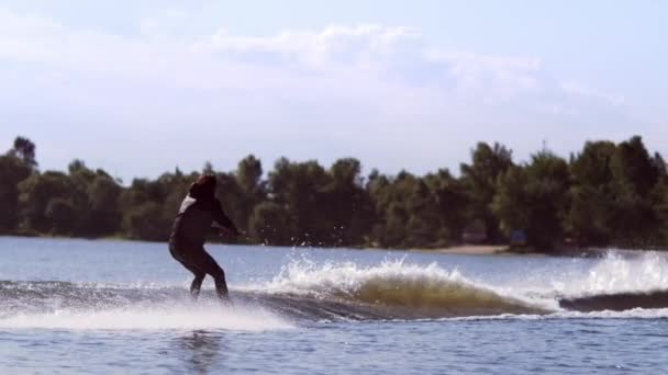 Man wakeboarding on waves. Water skiing on lake behind boat. Wakeboarder surfing — Stock Video