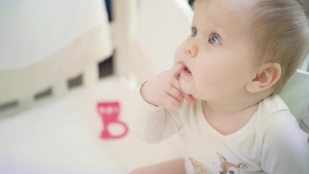 Bebé sentado na cama e a crescer o dedo. Criança pequena insatisfeita — Vídeo de Stock