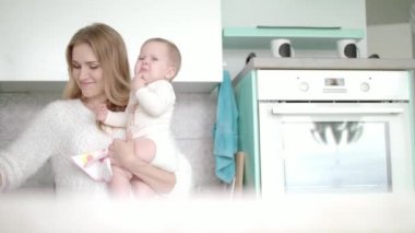 Bebekli anne beyaz mutfağa giriyor. Küçük çocuğu olan güzel bir kadın.