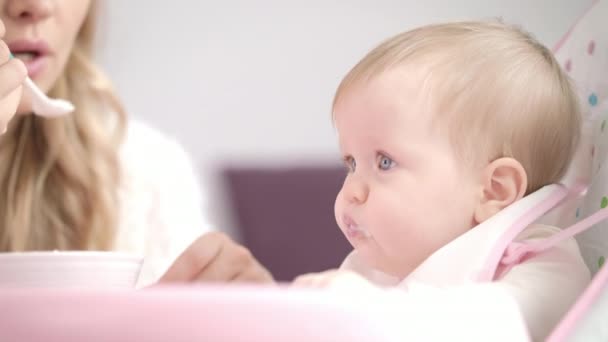 Bebé comiendo puré con cuchara. Madre que alimenta al niño con gachas — Vídeo de stock