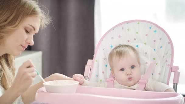 Mamá joven alimentando al bebé con cuchara. Madre alimentando al niño — Vídeo de stock