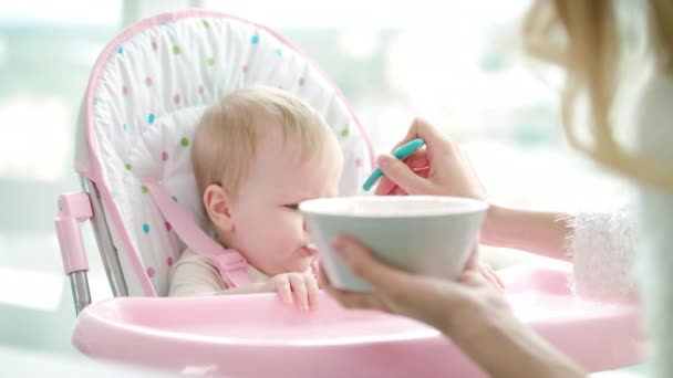 Mother feeding child with baby food. Toddler girl eat pureed food — Stock Video