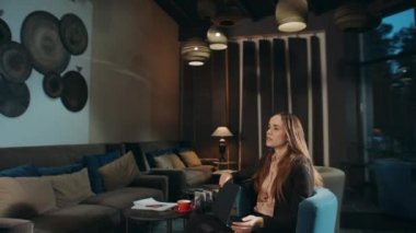 Otel lobisinde dizüstü bilgisayarı kapatan yorgun bir kadın. Kafedeki bitkin kadın.