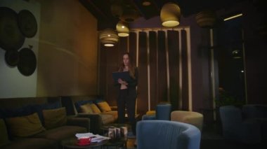 Stresli iş kadını, akşam otel odasında dizüstü bilgisayarla yürüyor.