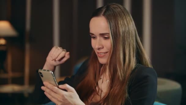 Mujer sonriente haciendo videollamada en el teléfono móvil en la sala de estar — Vídeos de Stock