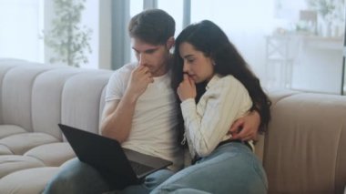 Genç çift evde ağır çekimde video seyrediyor. Şok olmuş insanlar haberleri izliyorlar.