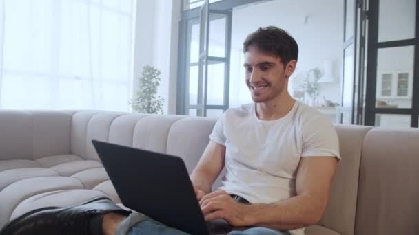 Vreugdevolle freelancer glimlachend naast de computer bij modern huis in slow motion. — Stockvideo