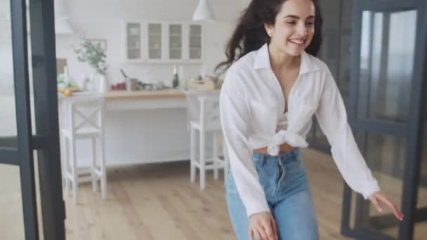 Eine lächelnde Frau läuft zu einem Mann nach Hause. fröhliches Mädchen springt in Zeitlupe auf Sofa — Stockvideo