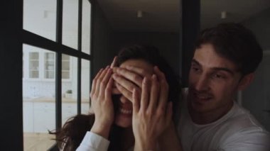 Eve giren genç bir ailenin portresi. Gülümseyen adam kadınlara gözlerini kapatıyor..